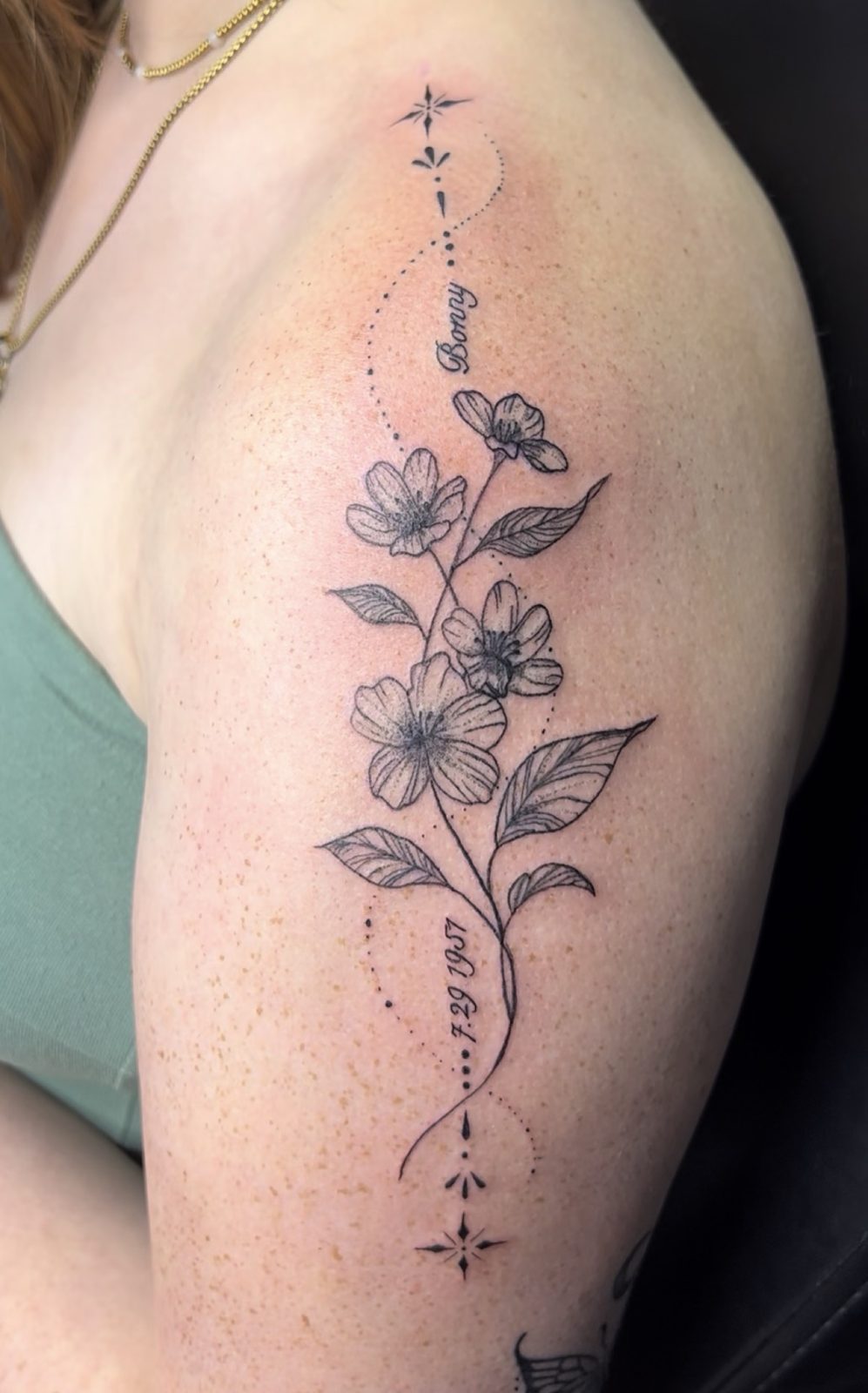 Fine line floral vine with a name and date on the upper arm